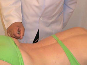 Kim examinando la zona lumbar de una paciente